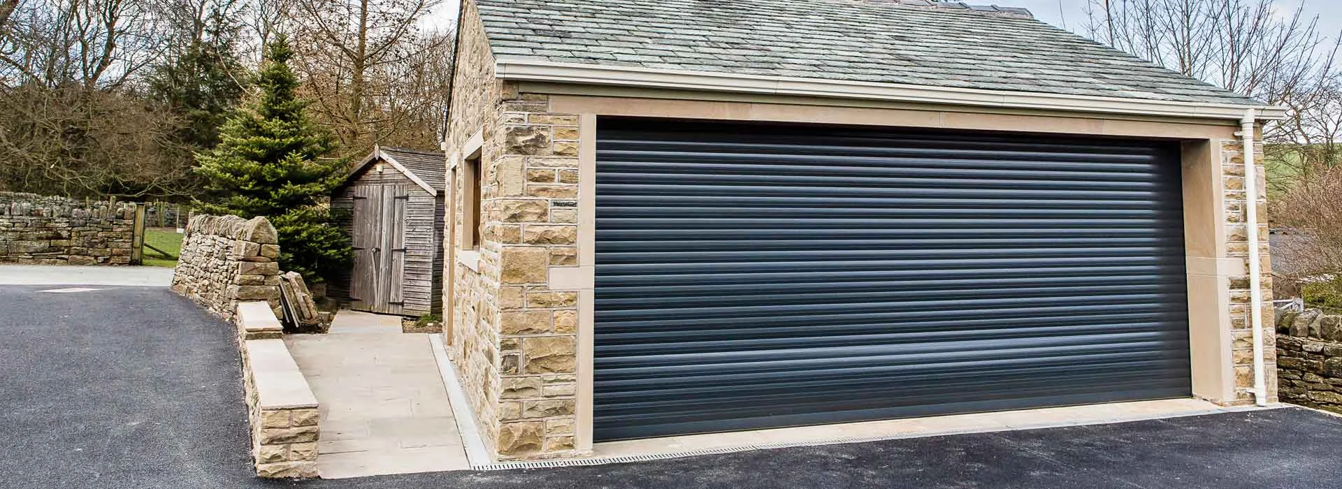 Stone garage with black roller door